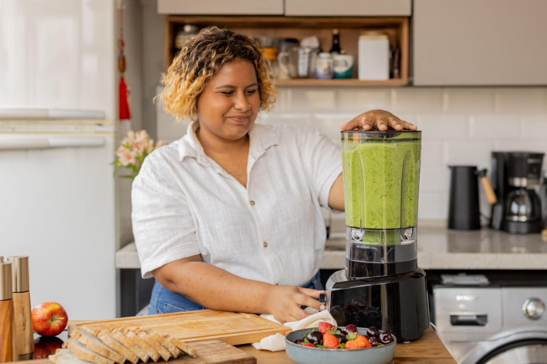 Mulher preparando suco verde saudável na cozinha